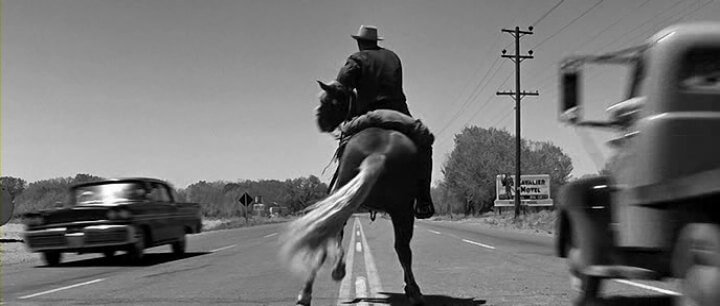 Kirk Douglas nei panni di Jack Burns mentre attraversa l'autostrada a cavallo.